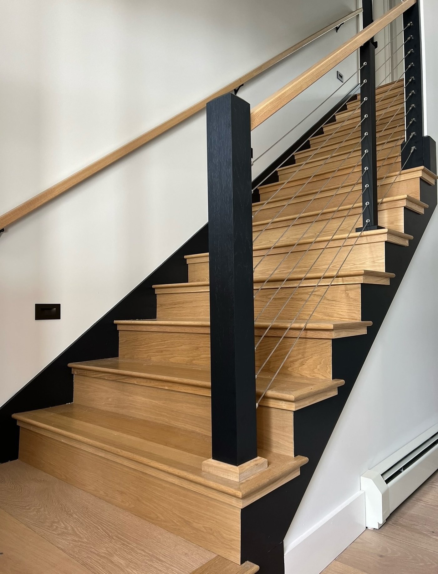 Custom white oak staircase with black cable railing in an O'Connell Builders home